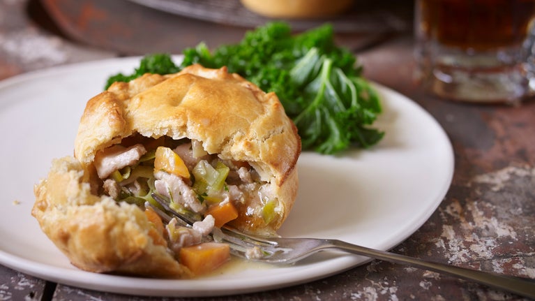 Chicken, leek and tarragon pie on a plate with a fork